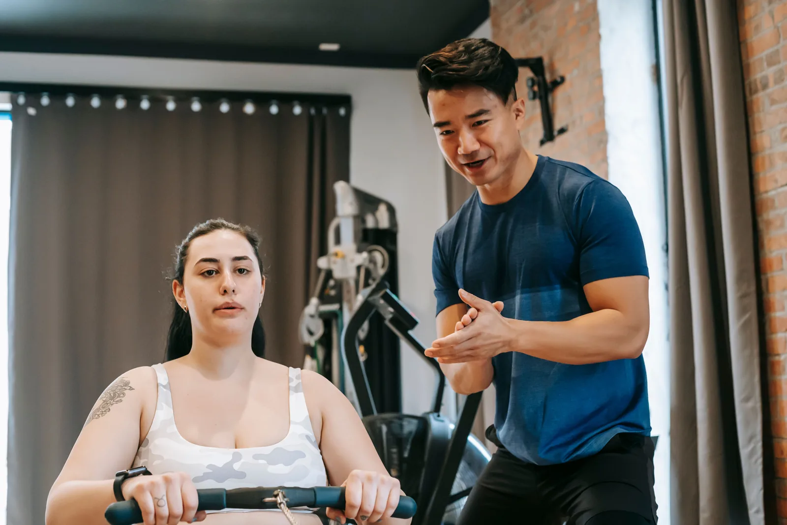 Entrenador acompañando a una alumna durante una sesión de gimnasio
